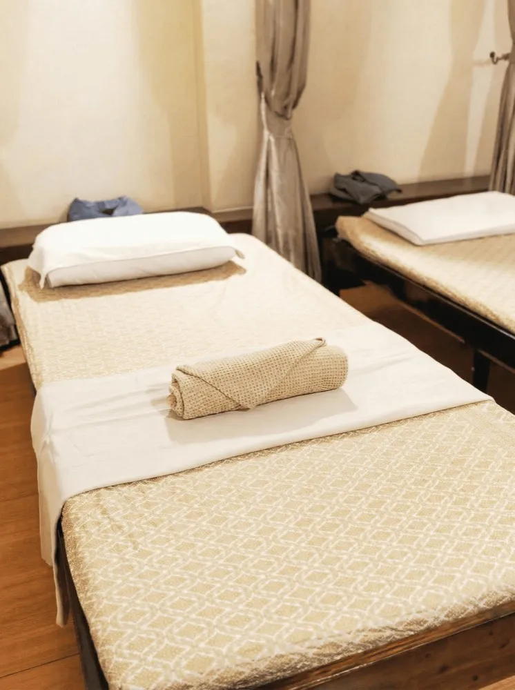 Massage bed with fresh linens and a rolled towel